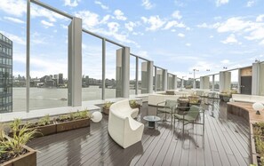 A rooftop terrace with modern seating, large windows, and a view of the city. - Stylish 1-bed Apartment in London (London)