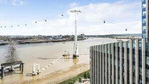 A modern building with a glass facade overlooking a river and a cable car system. - Stylish 1-bed Apartment in London (London)