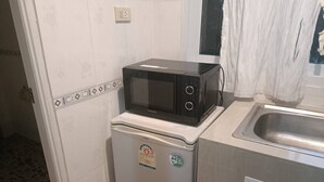 A compact kitchen with a microwave on a small refrigerator, a sink, and a tiled backsplash. - Private house one bedroom, full furniture, small kitchen, 5 minutes to the beach (Koh Samui)