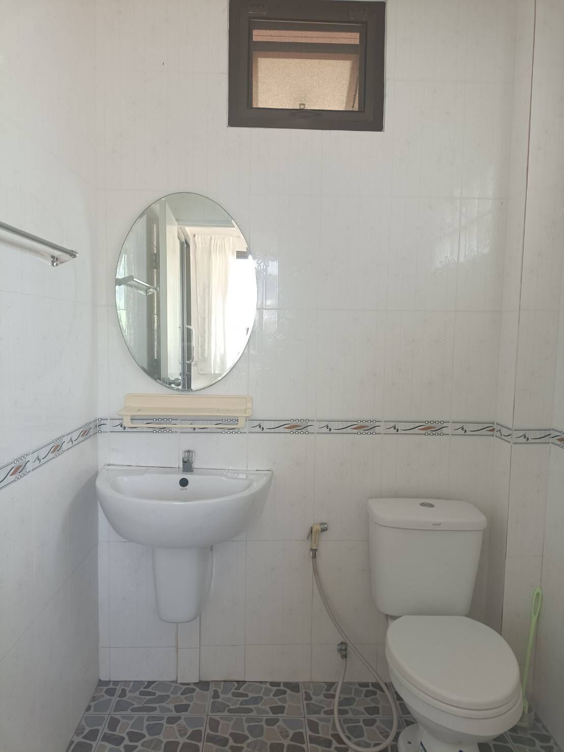 Une salle de bain avec un lavabo sur colonne, des toilettes et un miroir au-dessus du lavabo.
