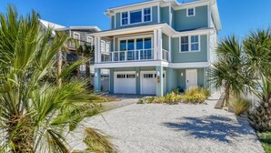 A two-story beachfront house with a covered patio, a garage, and a driveway leading to the entrance. - Good Vibes Villa (St. Augustine)