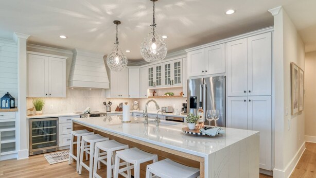 A modern kitchen with white cabinetry, a large island with bar stools, stainless steel appliances, and pendant lighting. - Good Vibes Villa (St. Augustine)