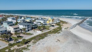 A coastal residential area with beachfront properties, including houses with balconies and a beach access road. - Good Vibes Villa (St. Augustine)