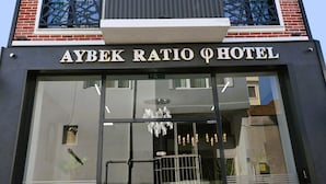 Exterior del hotel Aybek Ratio, con fachada moderna que combina ladrillo y elementos metálicos, ventanas amplias y una entrada destacada con puerta de cristal y rejas.