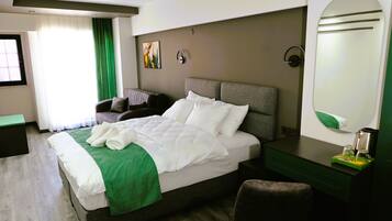 Una habitación de hotel con cama, escritorio, silla, espejo y ventana con cortinas.