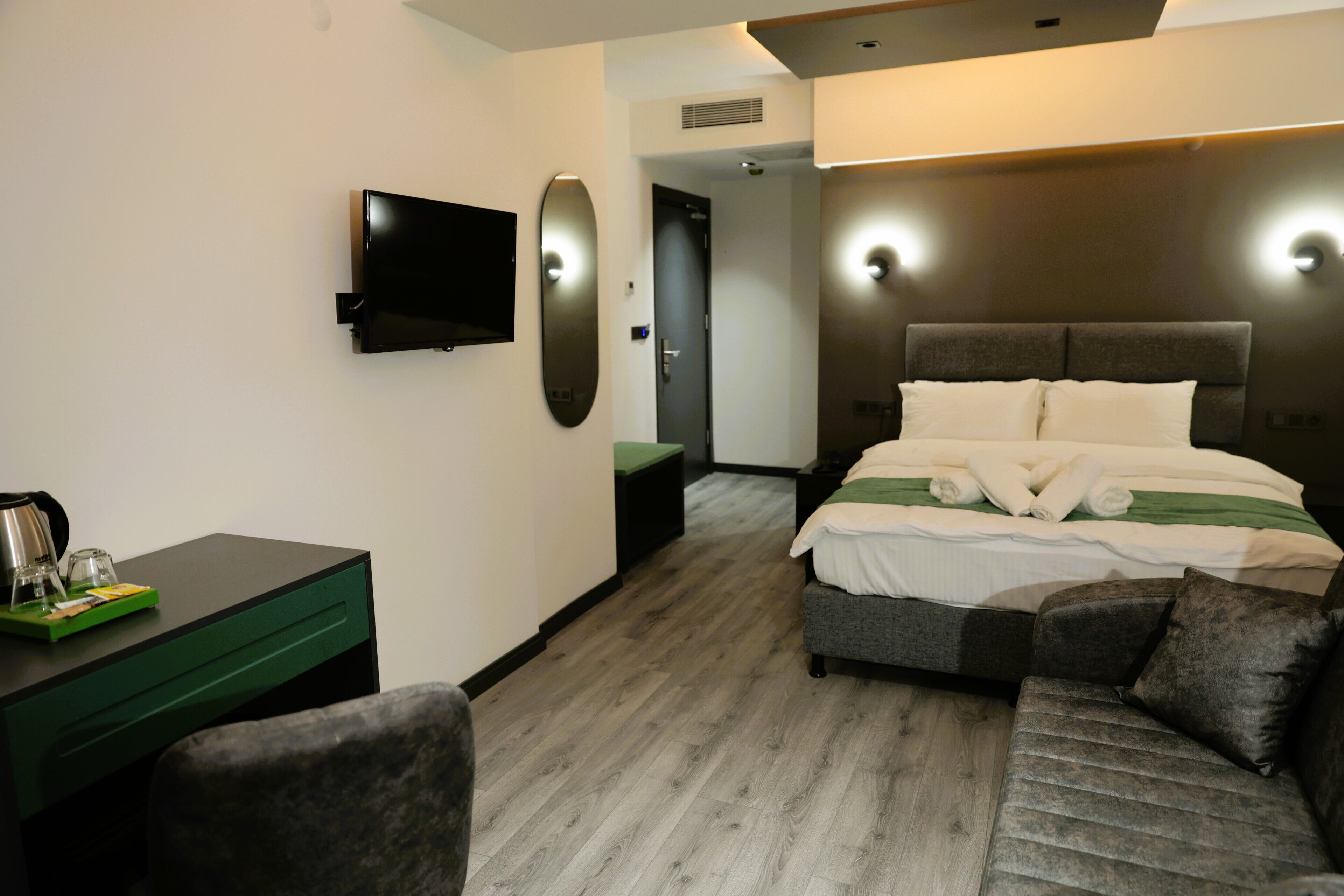 Una habitación de hotel moderna con cama, escritorio, silla, televisión de pantalla plana y espejo.