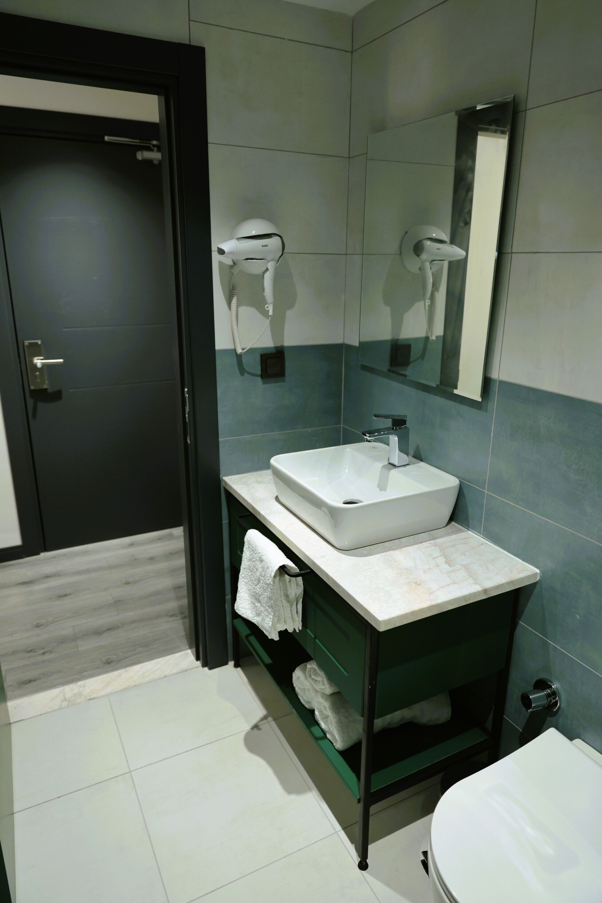 Un baño moderno con un lavabo blanco, un perchero y un inodoro.