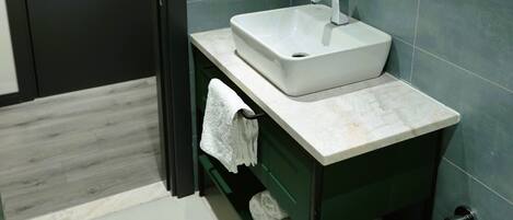 Un baño moderno con un lavabo blanco, un perchero y un inodoro.