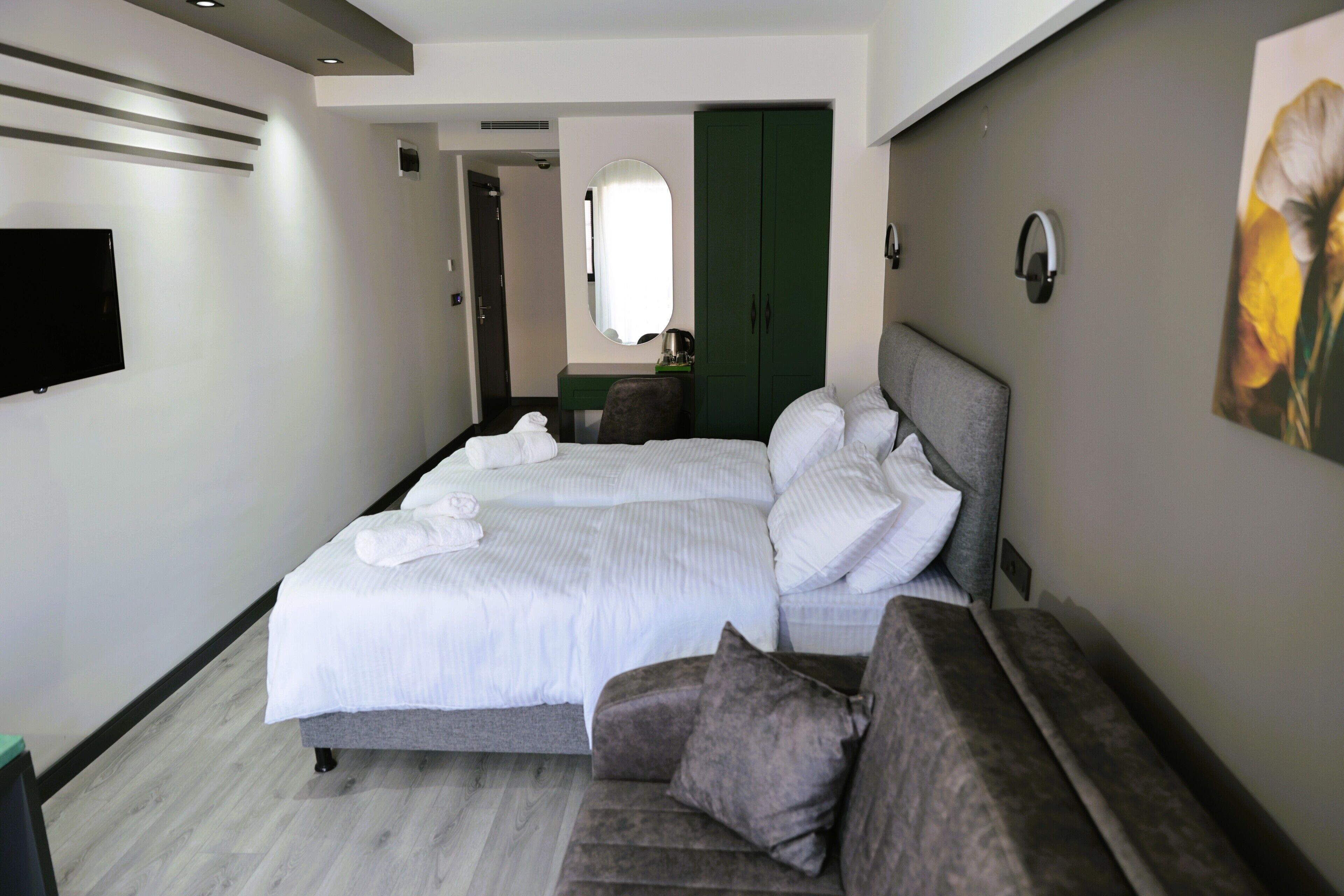 Una habitación de hotel moderna con una cama grande, un sofá, un televisor de pantalla plana y un armario verde.