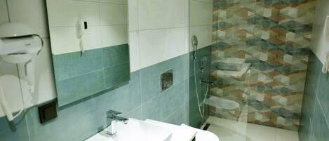 A modern bathroom with a white sink, a mirror, a toilet, and a shower with a geometric tile backsplash.