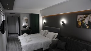Una habitación de hotel moderna con una cama grande, un sofá, un espejo y una lámpara de pared.