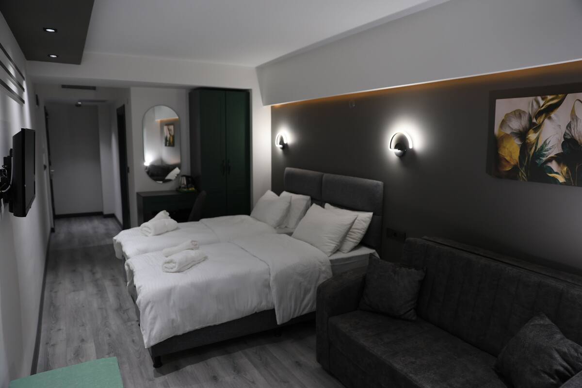 Een moderne hotelkamer met een groot bed, een bank, een spiegel en een wandlamp.