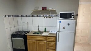 A compact kitchen with a gas stove, oven, microwave, and refrigerator. - Taminaka Condominium Comfortable II (Oranjestad)