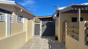 A narrow pathway leading to a gated entrance with a metal gate and a potted plant. - Taminaka Condominium Comfortable II (Oranjestad)