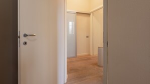 A hallway with a closed door, a radiator, and a light switch on the wall.