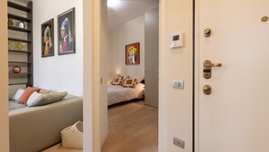 A modern bedroom with a sofa, a bed, and a hallway leading to another room.