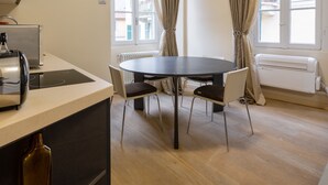 A modern kitchen with a built-in stove, a dining table with chairs, and a window with curtains.