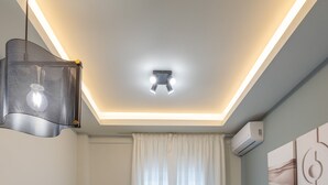 A modern living room with a flat-screen TV, a sofa, a coffee table, and a dining area with a glass top. - Modern Apt. ideal for families/couples,10 mins from Thessaloniki's vibrant heart (Thessaloniki)