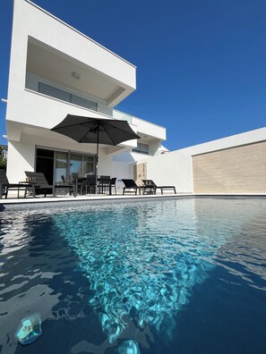 Un edificio moderno de dos pisos con piscina delantera.