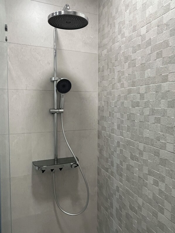 Ducha con cabezal de ducha manual y mandos en la pared.