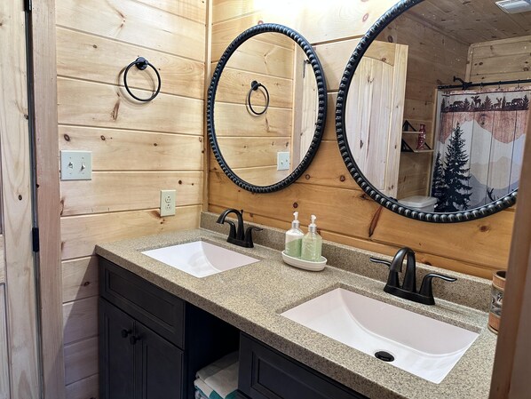 Un baño con dos lavamanos, paredes de madera y un espejo grande.