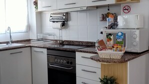A modern kitchen with white cabinets, a built-in oven, a microwave, and a coffee machine. - Sol y Playa Oliva (VC)