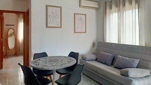 A modern living room with a round table, black chairs, a grey sofa, and two framed artworks on the wall. - Sol y Playa Oliva (VC)