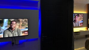 Une chambre d’hôtel avec un téléviseur fixé au mur diffusant une émission de CNN.