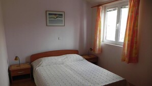 A single bed in a room with a window, a nightstand, and a lamp. - Apartments Trogrlić - One-Bedroom Apartment with Balcony (Hvar)