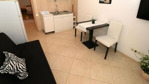A compact living space with a kitchenette, a dining table, and a sofa. - Apartments Trogrlić - One-Bedroom Apartment with Balcony (Hvar)