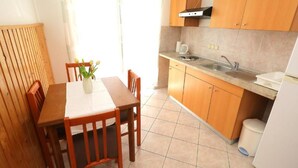 A compact kitchen with wooden cabinets, a white countertop, and a tiled floor.
