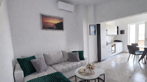 Ein modernes Wohnzimmer mit einer Couch, einem runden Couchtisch und einem Sonnenuntergangsbild.