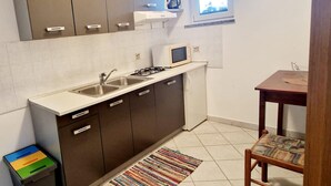 A compact kitchen with a gas stove, two sinks, a microwave, and a small window. - Apartments Sunset - Two bedroom Apartment (Porec)