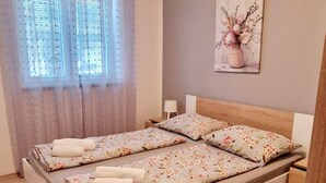 A double bed with floral bedding, a nightstand, a lamp, and a painting of flowers on the wall. - Apartments Sunset - Two bedroom Apartment (Porec)