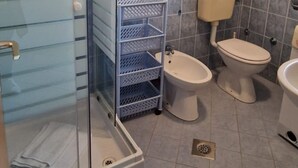 A bathroom with a glass shower enclosure, two toilets, a bidet, and a white sink. - Apartments Sunset - Two bedroom Apartment (Porec)