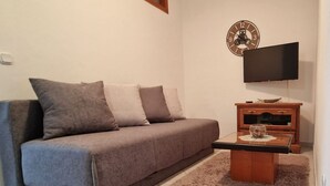 A living room with a sofa, a coffee table, a TV, and a clock on the wall. - Apartments Sunset - Two bedroom Apartment (Porec)