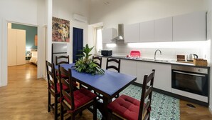 Een moderne keuken met witte kasten, een blauwe tafel en rode fauteuils.