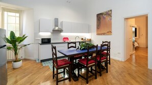 Een moderne keuken met witte kasten, een ingebouwde magnetron en een rode stoel.