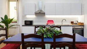 Een moderne keuken met witte kasten, een roestvrijstalen afzuigkap, een rode toaster en een eettafel met stoelen.