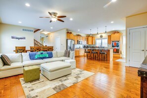 A spacious living room with a sectional sofa, ottoman, and a ceiling fan. - Spacious South Bend Home - Walk to Notre Dame! (South Bend)