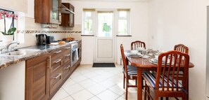A kitchen with wooden cabinets, a marble countertop, and a dining table set for four.