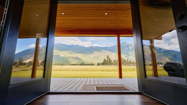 A modern interior with a wooden ceiling and large glass doors leading to a deck with a mountain view.