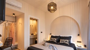 A modern bedroom with a bed, bedside tables, a hanging light fixture, and a wardrobe. - Sugarwhite Suites (Santorini)