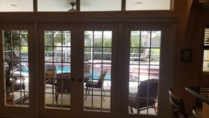 A view through a glass door with a pool and outdoor seating area visible.
