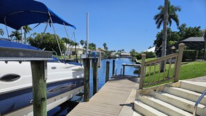 A marina with boats docked, a wooden walkway, and a clear sky.