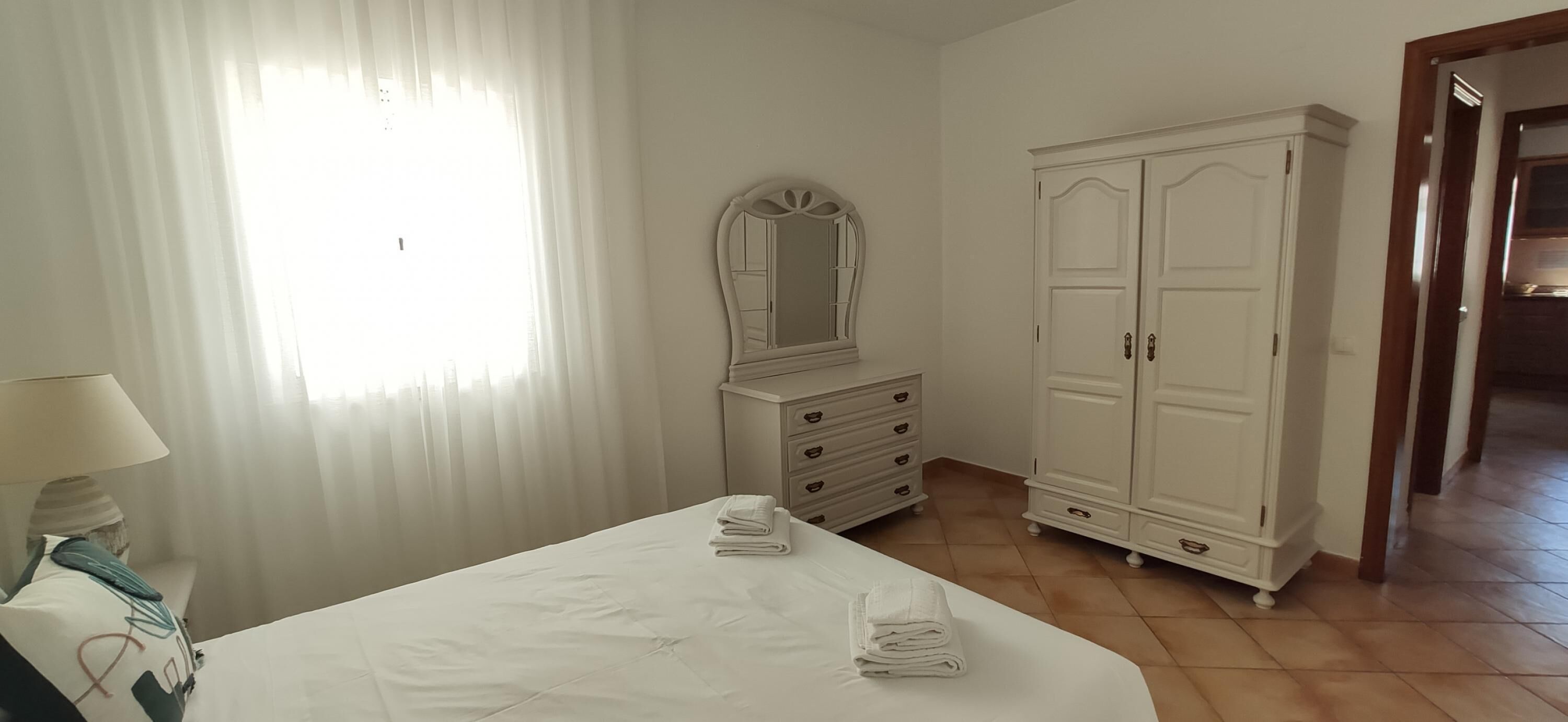 A bedroom with a bed, a dresser, a mirror, and a wardrobe.