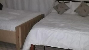 Un dormitorio con dos camas, piso estampado y cortina blanca.