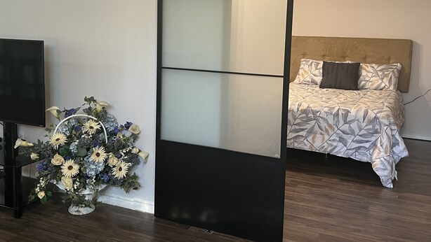 Ett modernt sovrum med en säng, en tv och en dekorativ blomsteruppsättning.