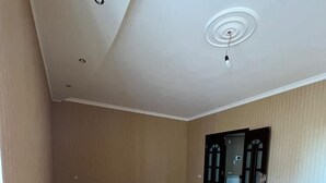 A spacious room with wooden flooring, a white ceiling with recessed lighting, and a door leading to another area. - Deluxe seaside Batumi  (Batumi)