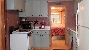 A compact kitchen with white cabinets, a stove, and a refrigerator.